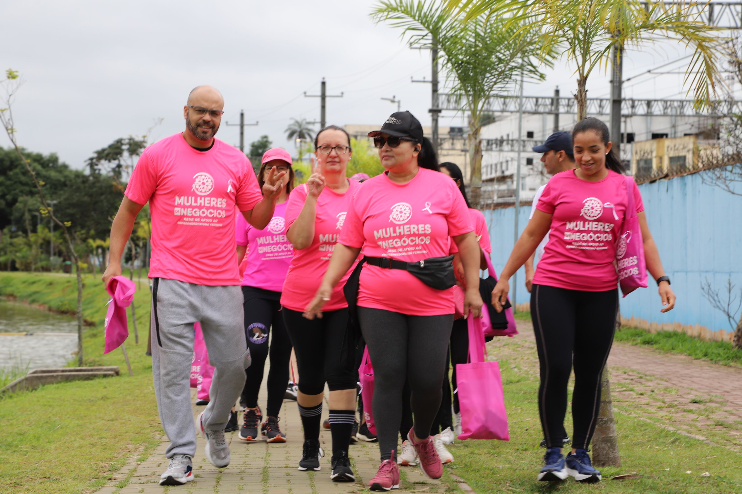 Participantes de camiseta rosa caminhando juntas